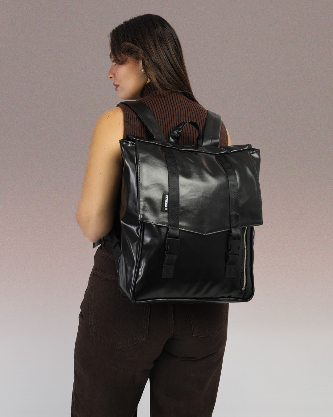 תיק גב טוקיו בצבע שחור מבריק על גב של דוגמנית, תיק טבעוני עם עיצוב פרקטי ומוקפד, מתאים לגבר ולאישה.