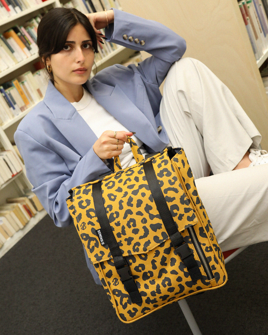 סטודנטית מחזיקה ביד תיק גב מיני טוקיו מנומר קלאסי של זנדיגי, הדפס שהם עושים בעצם בסטודיו, התיק הוא תיק גב ללימודים, למשרד או לעבודה.