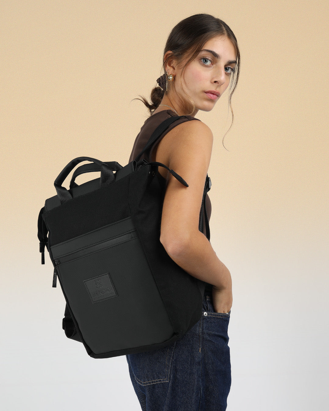 תיק גב מיני שחור בצבע שחור קנבס ודמוי עור תיק למחשב עד 14״ על גב של דוגמנית, תיק מרופד למחשב נייד תיק גב ללפטופ, מושלם ללימודים ולעבודה, תיק לסטודנטים, תיק גב מעוצב לאישה