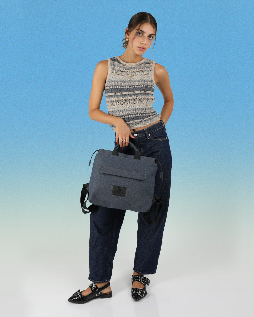 דוגמנית מחזיקה בידית נשיאה את תיק מדריד ג׳ינס, תיק יפייפה איכותי ומתאים לסטודנטים, תיק טבעוני מיוצר ומעוצב בישראל בעוד הבדים האיכותיים מהם עשוי מגיעים מאיטליה