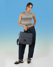 דוגמנית מחזיקה בידית נשיאה את תיק מדריד ג׳ינס, תיק יפייפה איכותי ומתאים לסטודנטים, תיק טבעוני מיוצר ומעוצב בישראל בעוד הבדים האיכותיים מהם עשוי מגיעים מאיטליה