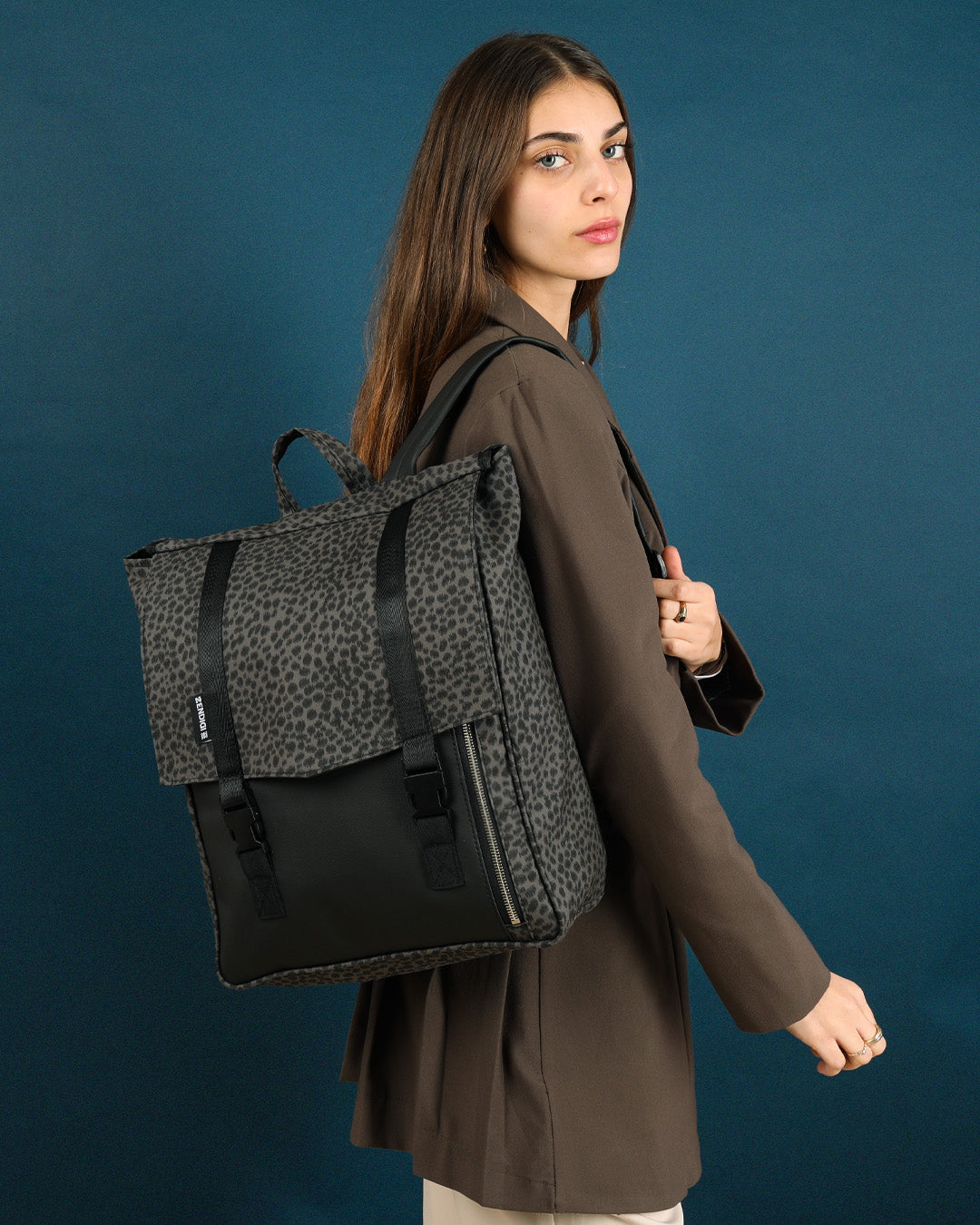 תיק גב טוקיו אפור מנומר על גב של דוגמנית, תיק טבעוני עם עיצוב פרקטי ומוקפד, מתאים לגבר ולאישה.