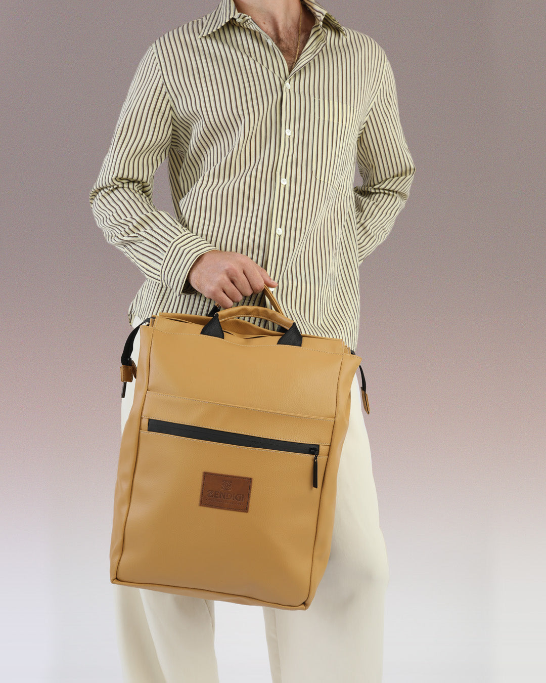 מילאנו קאמל - תיק גב למחשב טבעוני של זנדיגי מוחזק בידיות הנשיאה שלו על ידי דוגמן, תיק גב לגבר, תיק טבעוני מרופד ללפטופ.