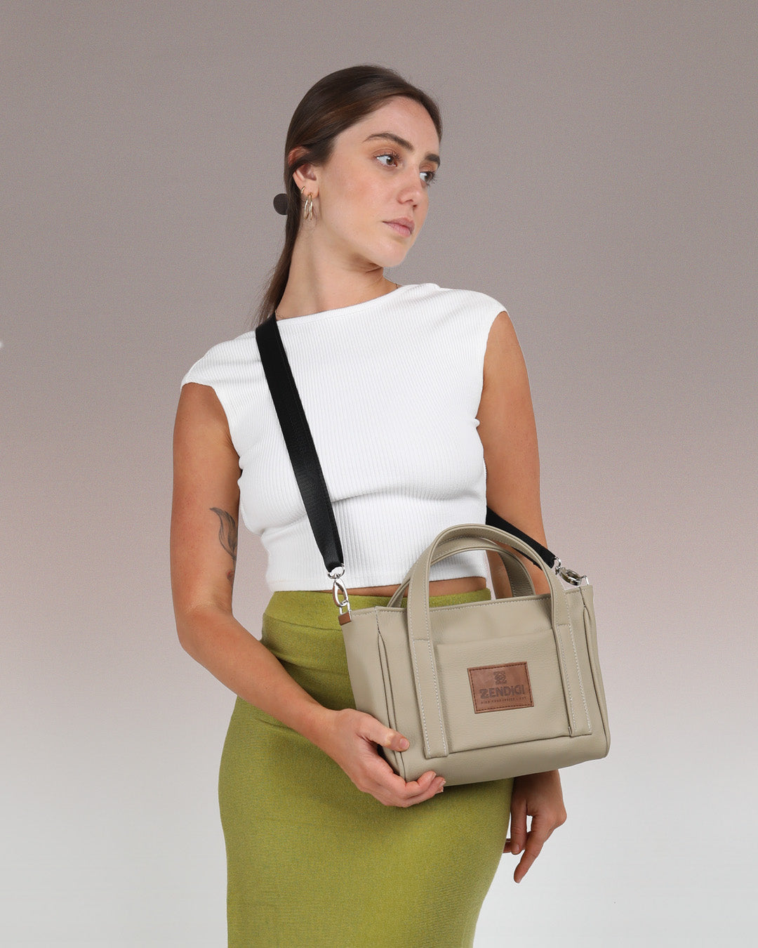 תיק קרוס באדי ויד מיקרו פלא בז׳ חאקי, תיק קטן שמכיל המון, ניתן להחזקה ולנשיאה על כתף מוצג על דוגמנית באופן פרונטלי