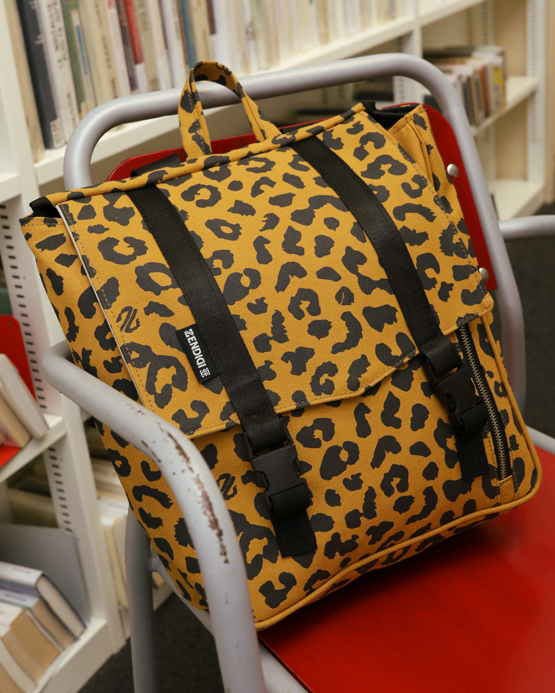 תיק גב בהדפס מנומר למחשב נייד קטן מיני טוקיו, תיק ללימודים, תיק ללפטופ, מונח על כיסא בספרייה