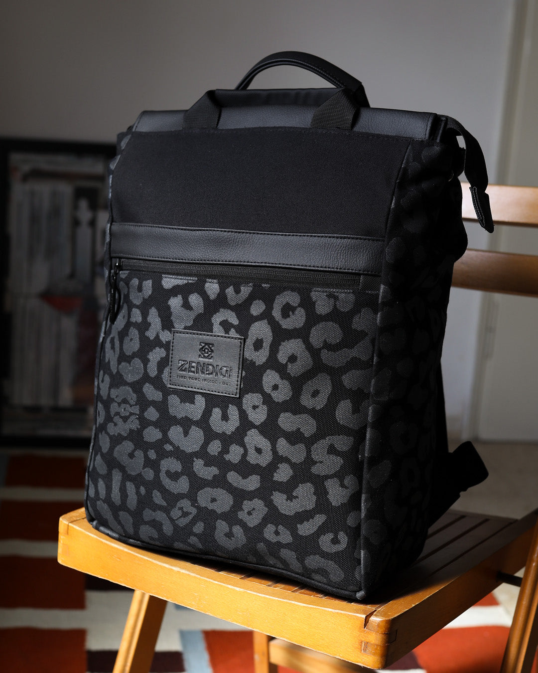 תקריב על תיק גב מרופד למחשב מדגם מילאנו עם הדפס מנומר שחור, מציג את רצועות האחיזה העליונות והרוכסנים האיכותיים