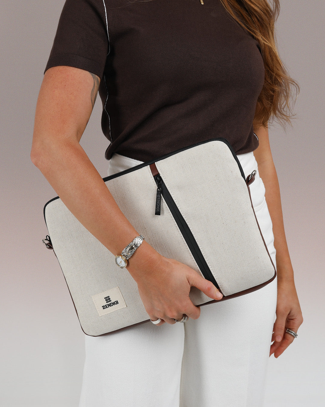 כיסוי למחשב נייד 13 14״ בז׳ וחום קנבס תצוגה פרונטלית מוחזק בידה של הדוגמנית