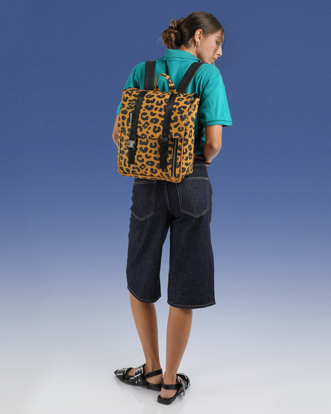 מיני טוקיו מנומר קלאסי, בהדפסה ידנית בסטודיו שלנו בתל אביב, תיק גב למחשב 14״ , טקסטורת נמר ייחודית לזנדיגי, תיק גב קטן למחשב, תיק גב מנומר צהוב תיק ללפטופ, תיק לאישה או לגבר מוצג על גב הדוגמנית כשניתן לראות את הפרופורציות שלו על גבה