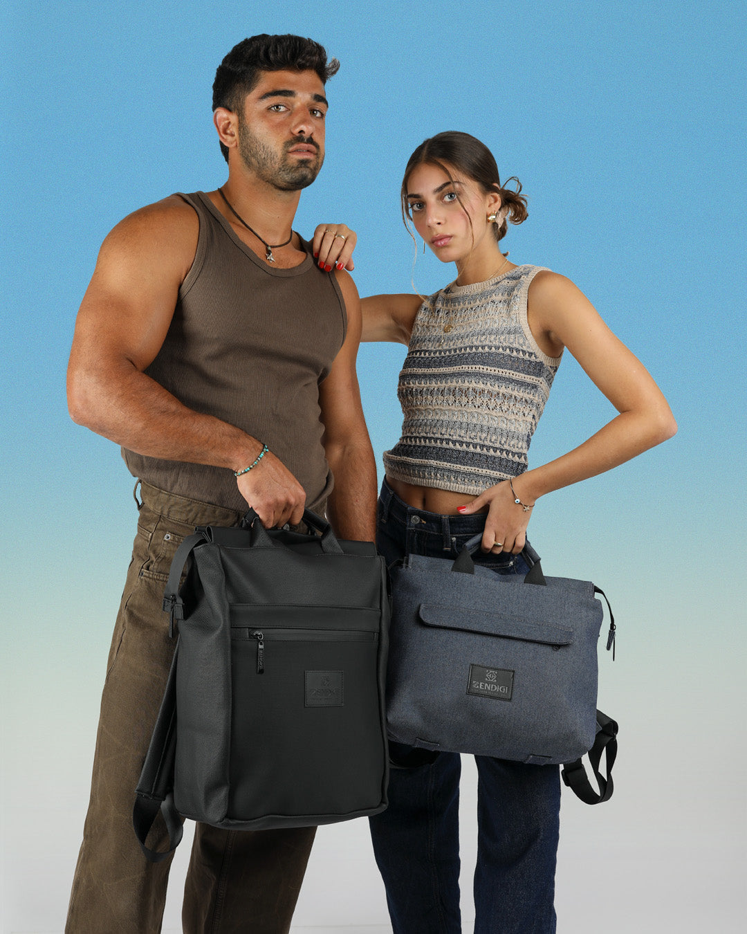 מדריד ג׳ינס, עשוי בד אריג עבה איכותי וחזק, תיק גב למחשב 14״ עם כיסוי למחשב בגב התיק, נוח, פרקטי ומושלם לעבודה במשרד או ליום מחוץ לבית, בתמונה דוגמן ודוגמנית, הבחור עם תיק מילאנו שחור יהלום והבחורה מחזיקה בידית הנשיאה את המדריד ג׳ינס.