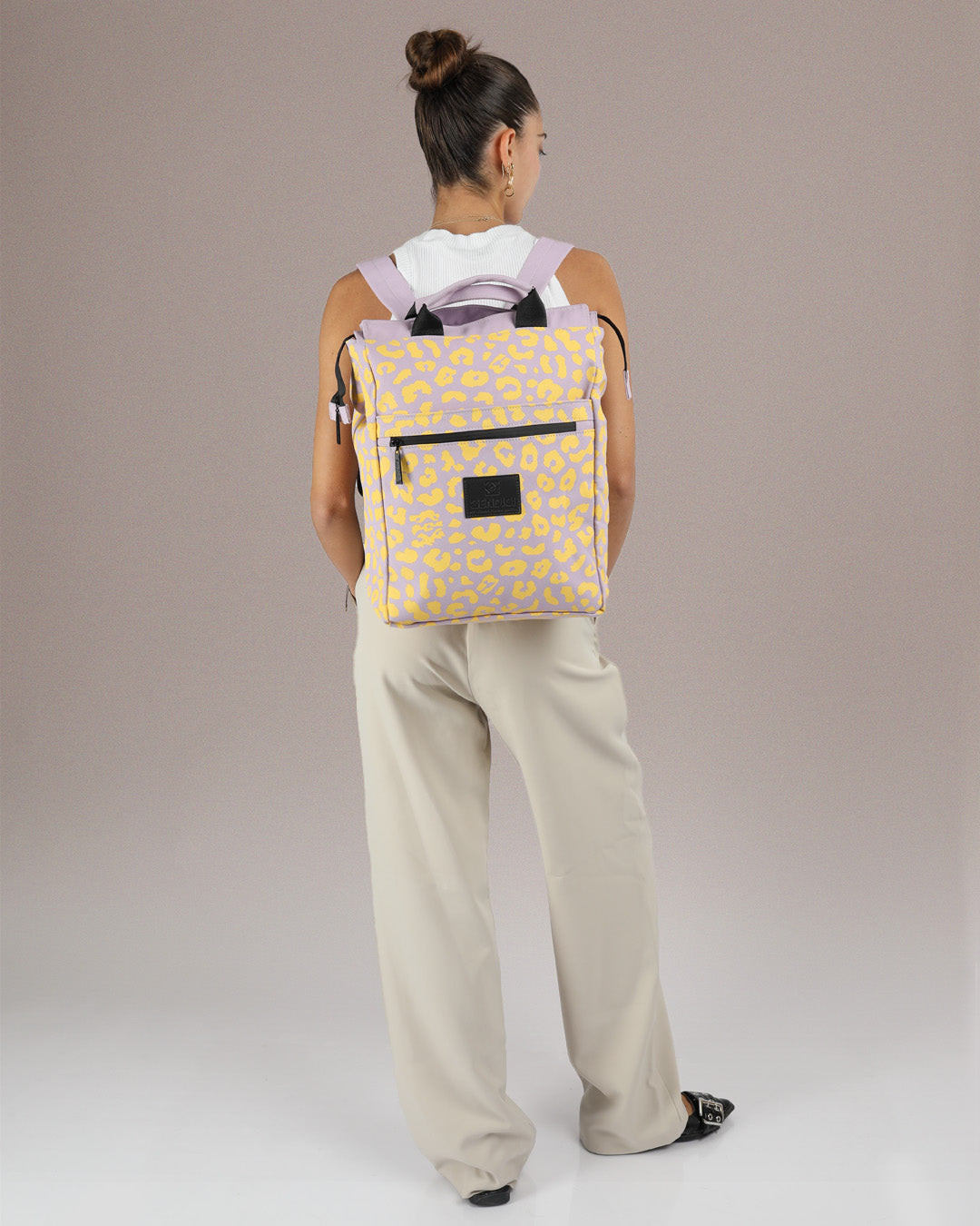 תיק גב למחשב סגול מנומר צהוב, תיק לפטופ ללימודים באוניברסיטה, תיק לסטודנטים, על דוגמנית, ניתן לראות את הפרופורציות של התיק על הדוגמנית