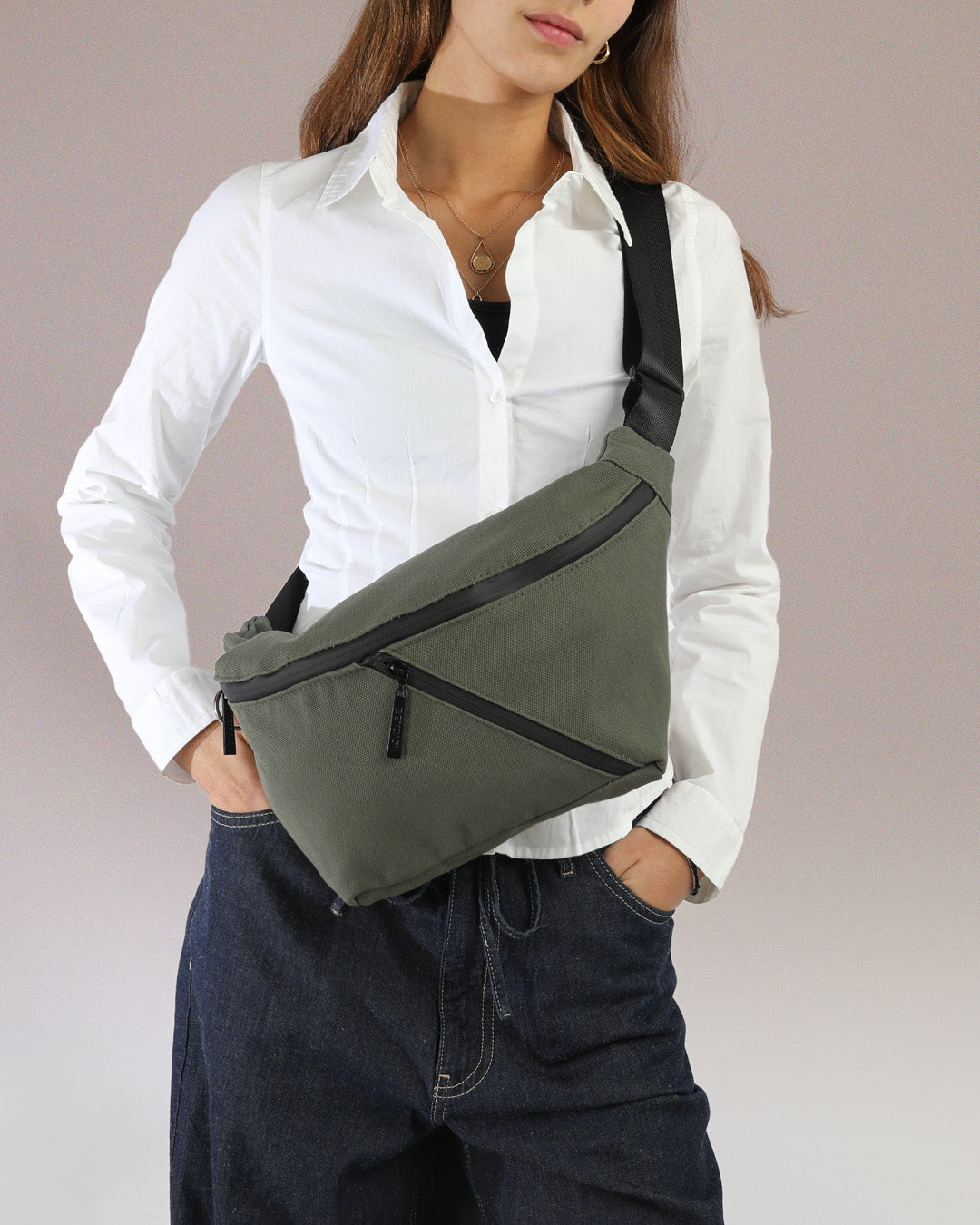 תיק פאוץ' רובר XL ירוק בד - תיק צד אופנתי עם רצועה מתכווננת, על דוגמנית בסטייל אורבני, נכנס בקבוק מים, ספר ואייפד, ניתן ללבוש גם כתיק צד על הכתף כפי שרואים בתמונה