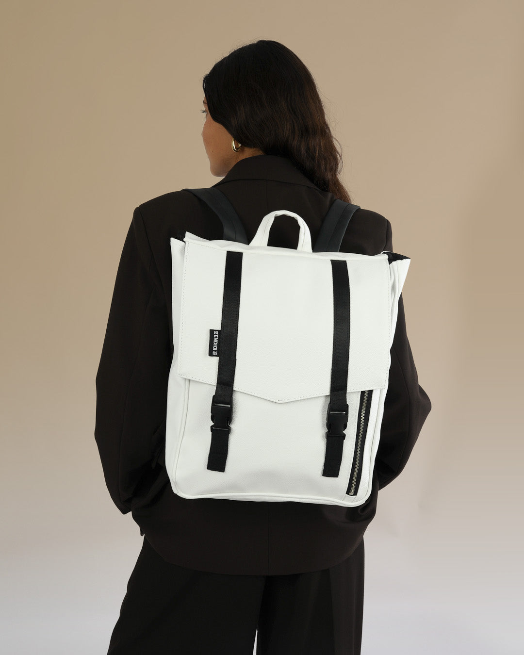 תיק גב טוקיו לבן קלאסי על גב של דוגמנית, תיק טבעוני עם עיצוב פרקטי ומוקפד, מתאים לגבר ולאישה.