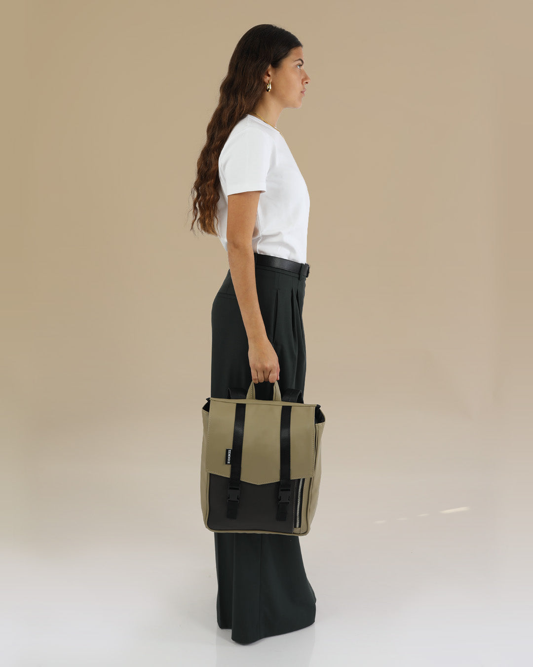 מיני טוקיו מדבר ושחור מוחזק בידה של דוגמנית, תיק גב טבעוני לאישה, תיק ללפטופ לגבר תיק גב איכותי.