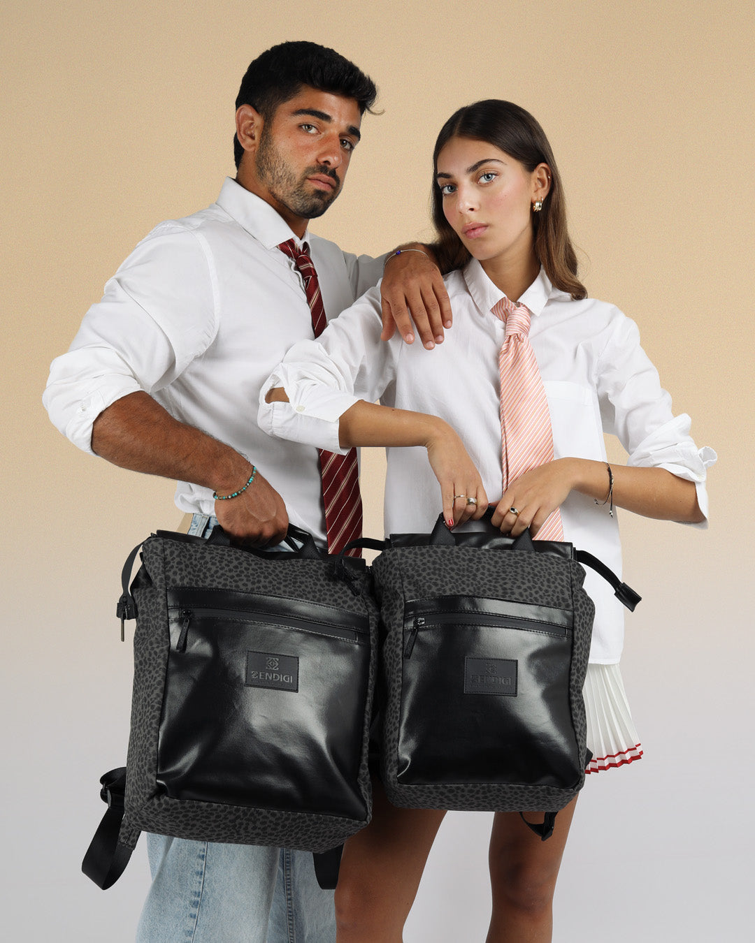 תיק גב למחשב נייד מילאנו אפור מנומר מוחזק בידית הנשיאה על ידי שני דוגמנים, הדוגמן. מחזיק מילאנו גדול והדוגמנית את דגם המיני מילאנו.