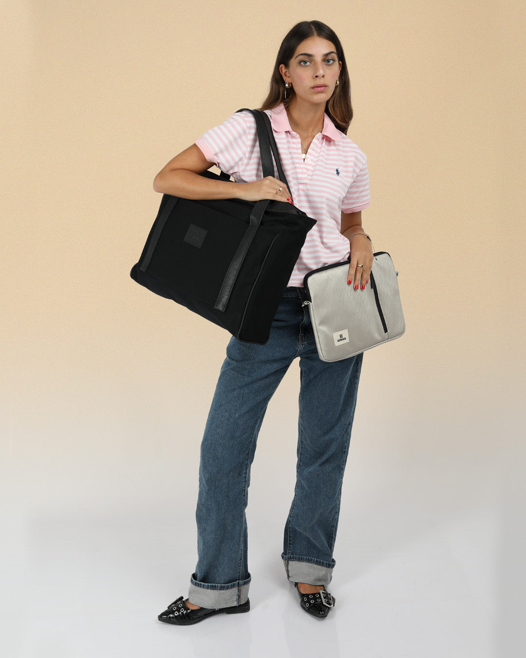 תיק צד למחשב נייד פלא שחור קנבס, תיק איכותי וחזק, מושלם לימי לימודים ארוכים, מאוד מתאים לסופשים וטיסות בחו״ל, תיק צד גדול שחור שיכול להכיל כמעט הכל מוצג על דוגמנית שמחזיקה אותו על הכתף וגם כיסוי למחשב נייד 14״ כסף קלאסי ביד השניה שלה