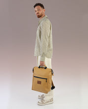 תיק גב למחשב קאמל לגבר, תיק לפטופ ללימודים באוניברסיטה, תיק לסטודנטים, על דוגמן מוחזק בידיות הנשיאה, ניתן לראות את הפרופורציות של התיק על הדוגמן.